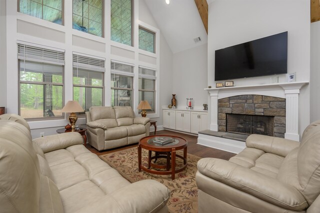 living room featuring dark wood-type flooring, a stone fireplace, high vaulted ceiling, and beam ceiling