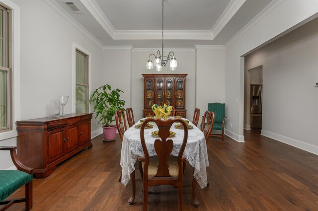 dining area featuring a notable chandelier, a tray ceiling, ornamental molding, and dark hardwood / wood-style floors