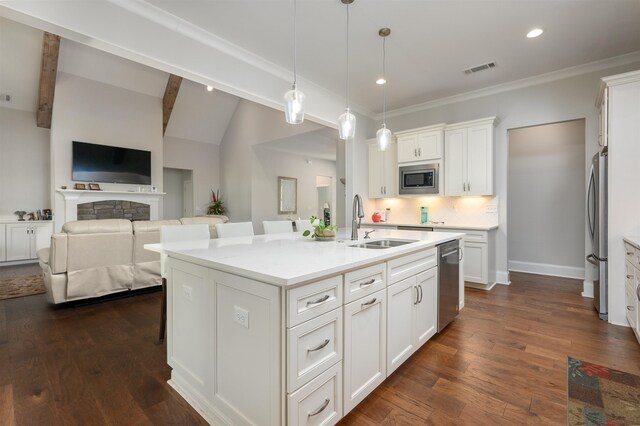 kitchen featuring pendant lighting, white cabinetry, sink, stainless steel appliances, and a center island with sink