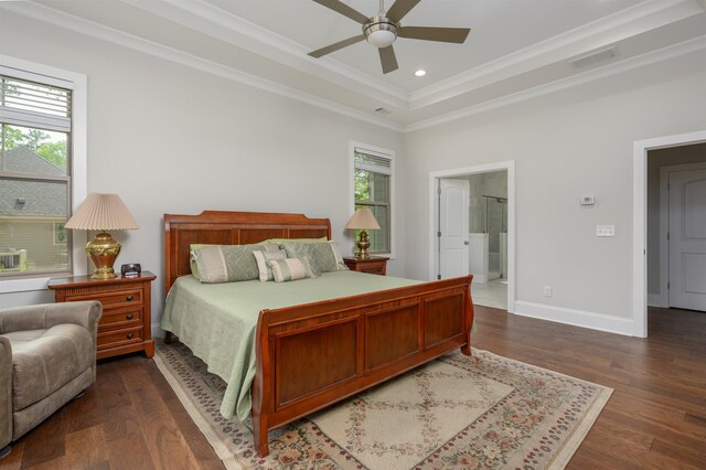 bedroom featuring dark hardwood / wood-style floors, connected bathroom, ornamental molding, ceiling fan, and a tray ceiling