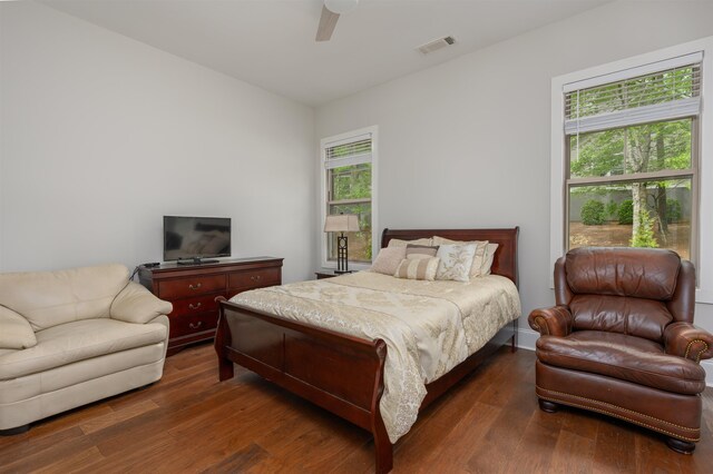 bedroom with multiple windows, ceiling fan, and dark hardwood / wood-style flooring