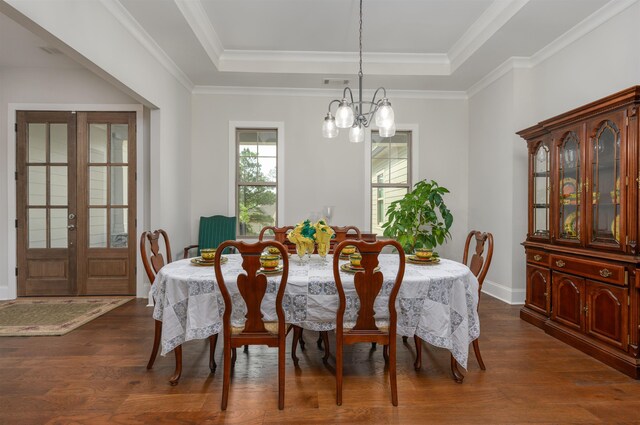 dining space with an inviting chandelier, dark hardwood / wood-style floors, a raised ceiling, and french doors