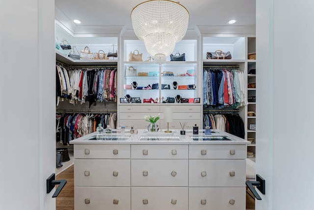 walk in closet with hardwood / wood-style flooring and an inviting chandelier