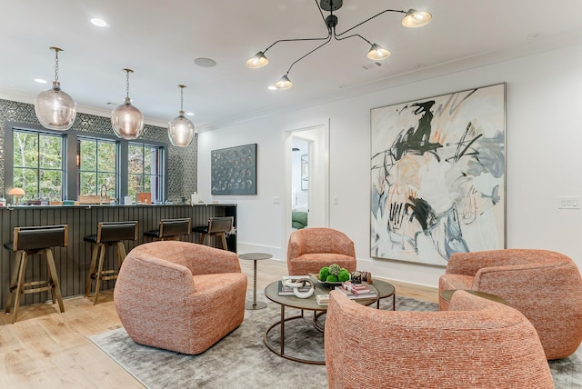 living room with bar, light hardwood / wood-style flooring, and ornamental molding