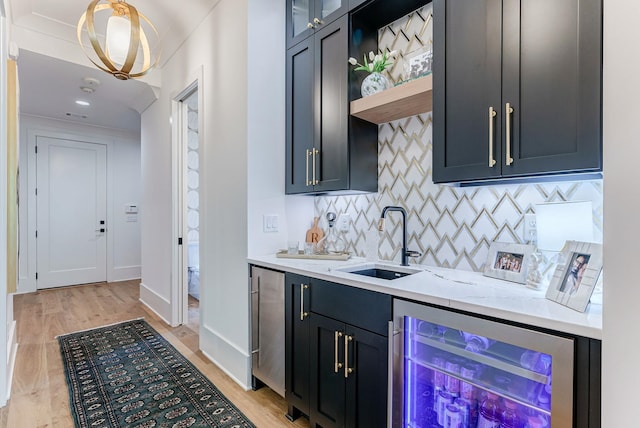 bar featuring wine cooler, sink, tasteful backsplash, hanging light fixtures, and light stone countertops