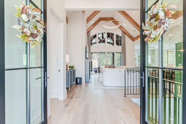 interior space featuring beam ceiling, high vaulted ceiling, and light hardwood / wood-style floors