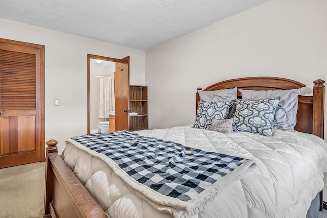 carpeted bedroom with a textured ceiling and ensuite bath