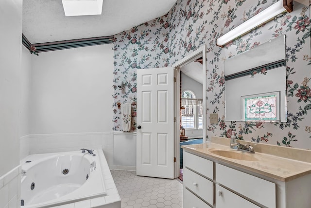 bathroom with a skylight, tile patterned flooring, vanity, a relaxing tiled tub, and a textured ceiling