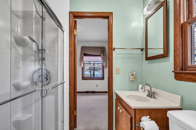 bathroom featuring vanity, toilet, a shower with shower door, and a textured ceiling