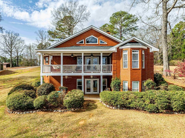 back of property with brick siding, french doors, a ceiling fan, and a yard