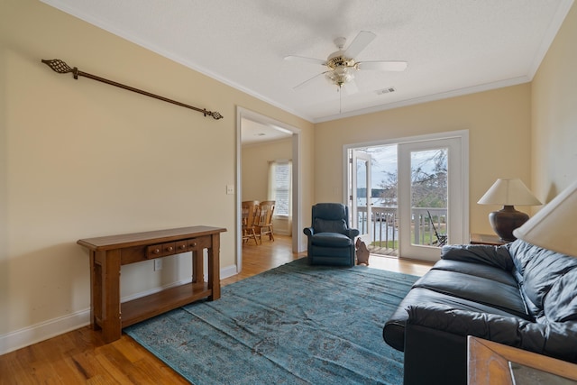 living room featuring ceiling fan, wood finished floors, baseboards, and ornamental molding