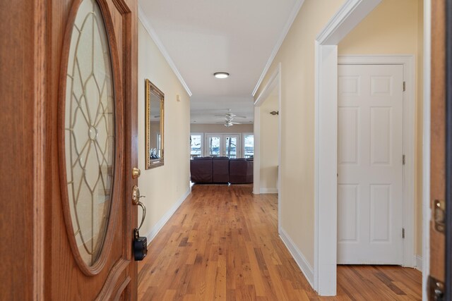 hall with baseboards, light wood-type flooring, and ornamental molding