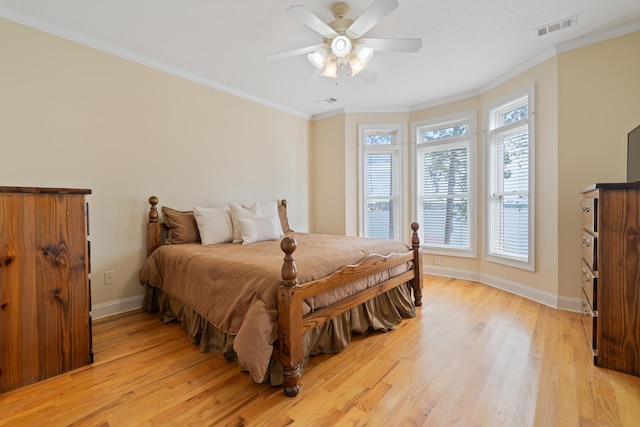 bedroom with light wood-style flooring, baseboards, visible vents, and ornamental molding