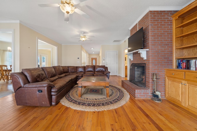 living room featuring crown molding, a brick fireplace, and light wood-type flooring