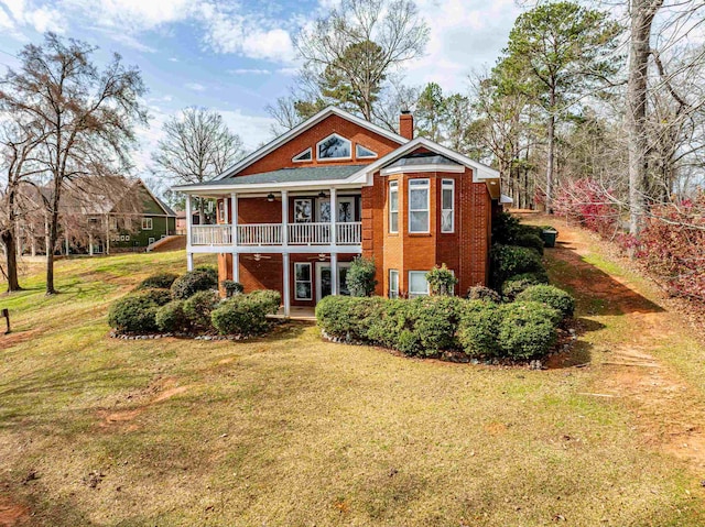 back of property featuring a lawn, brick siding, and a chimney