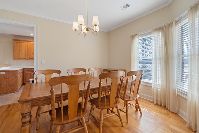 dining area with light wood-type flooring, visible vents, crown molding, baseboards, and a chandelier