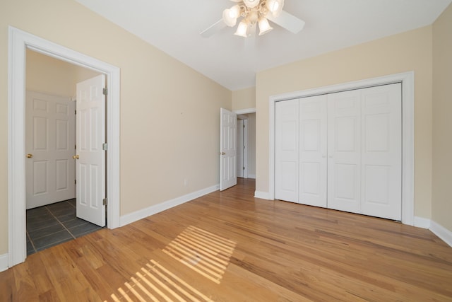 unfurnished bedroom featuring light wood finished floors, a closet, baseboards, and a ceiling fan