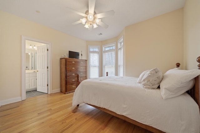 bedroom with a ceiling fan, visible vents, baseboards, ensuite bathroom, and light wood-type flooring