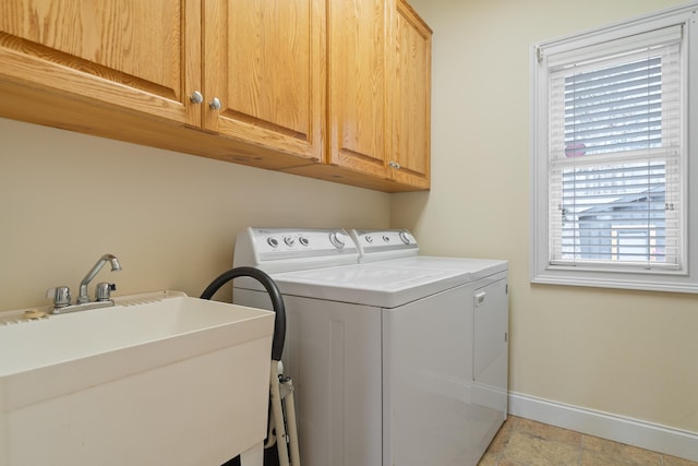 washroom with a sink, baseboards, cabinet space, and washing machine and dryer