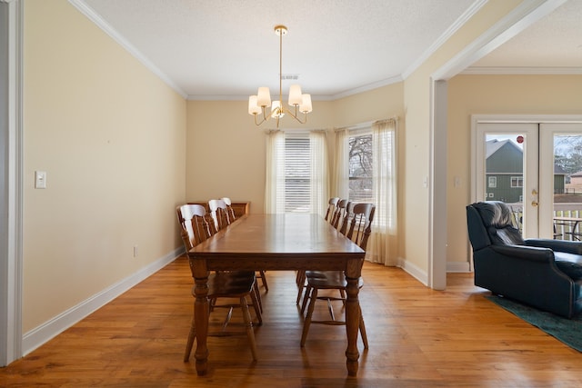 dining room with light wood-type flooring, baseboards, ornamental molding, and french doors