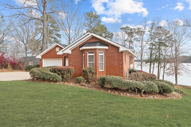 view of side of property featuring brick siding, a garage, driveway, and a yard