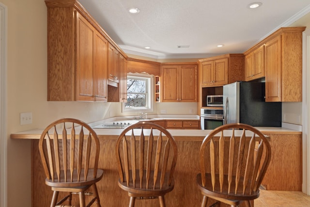 kitchen featuring a sink, stainless steel appliances, a peninsula, and light countertops