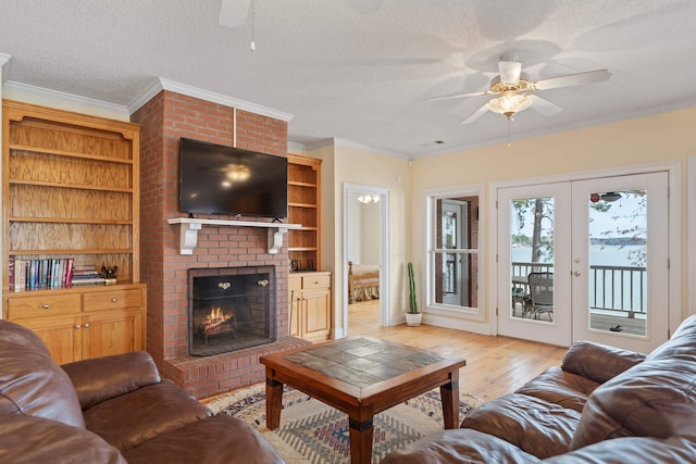 living area with crown molding, light wood-type flooring, french doors, a fireplace, and a textured ceiling