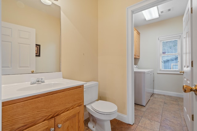 bathroom featuring baseboards, separate washer and dryer, vanity, and toilet