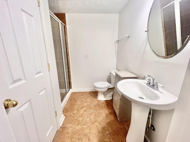 bathroom featuring a shower with shower door, tile patterned floors, toilet, and a textured ceiling