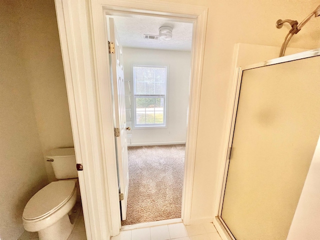 bathroom featuring a textured ceiling, tile patterned floors, toilet, and walk in shower