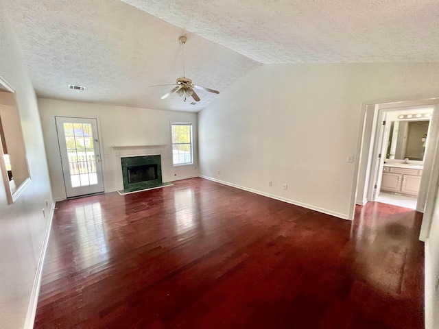 unfurnished living room featuring vaulted ceiling, a textured ceiling, dark hardwood / wood-style flooring, ceiling fan, and a high end fireplace