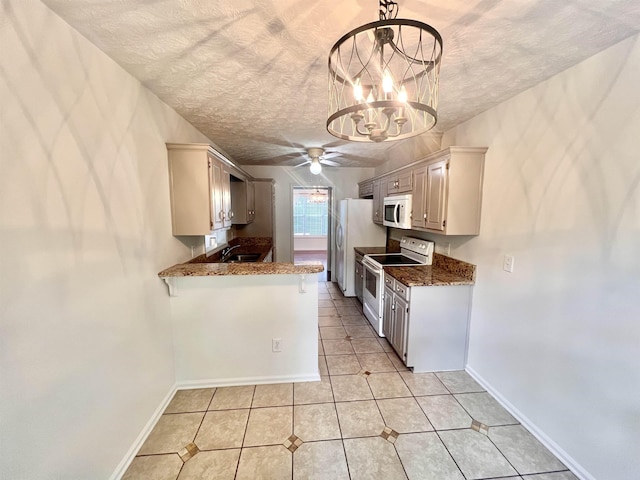 kitchen with hanging light fixtures, light tile patterned floors, white appliances, kitchen peninsula, and a textured ceiling