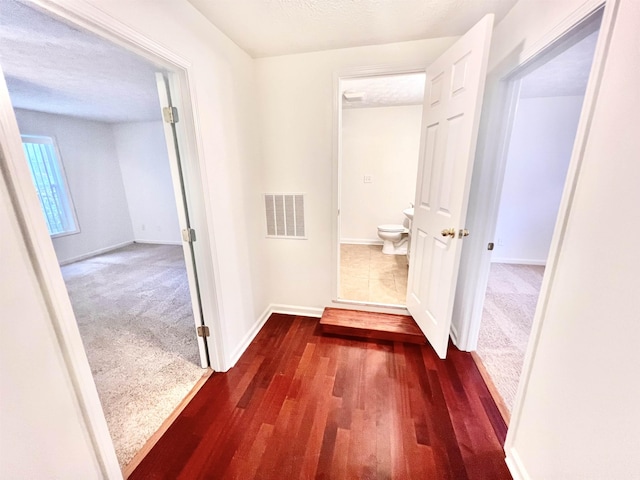 corridor featuring dark carpet and a textured ceiling