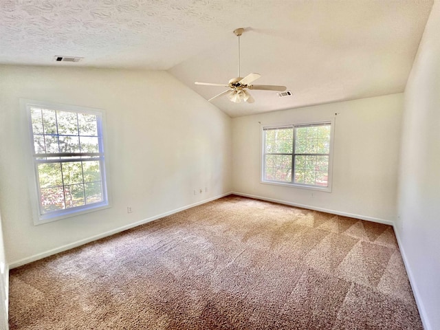 carpeted empty room with ceiling fan, vaulted ceiling, and a textured ceiling