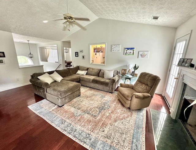 living room with ceiling fan, lofted ceiling, dark hardwood / wood-style floors, and a textured ceiling