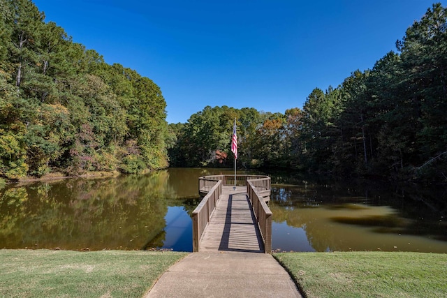 view of dock with a wooded view and a water view