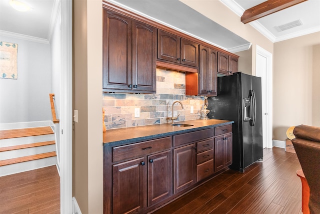 kitchen featuring dark wood-style floors, visible vents, ornamental molding, a sink, and black fridge