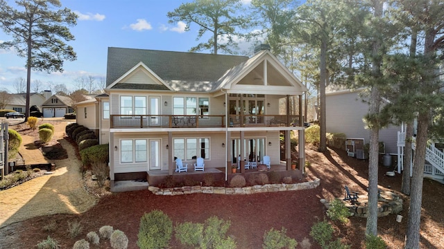 back of property with a patio area and roof with shingles