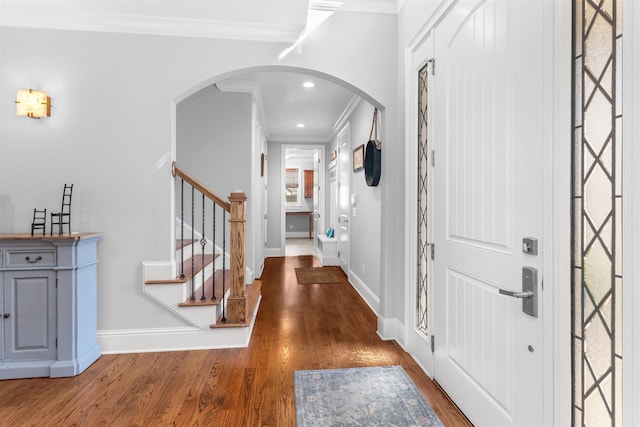 entryway featuring baseboards, wood finished floors, arched walkways, and ornamental molding