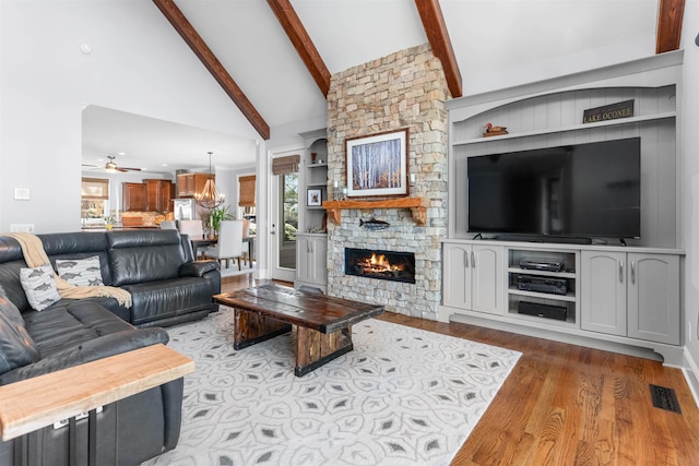 living room featuring visible vents, beamed ceiling, ceiling fan with notable chandelier, wood finished floors, and high vaulted ceiling