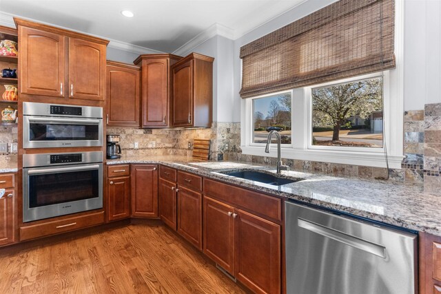 kitchen featuring a sink, decorative backsplash, light stone counters, and stainless steel appliances