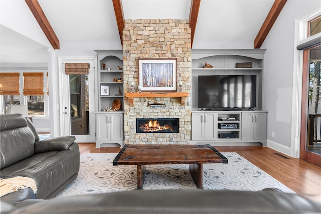 living room featuring visible vents, vaulted ceiling with beams, baseboards, a fireplace, and wood finished floors