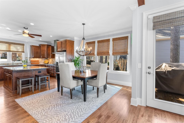 dining space featuring wood finished floors, baseboards, recessed lighting, crown molding, and ceiling fan with notable chandelier