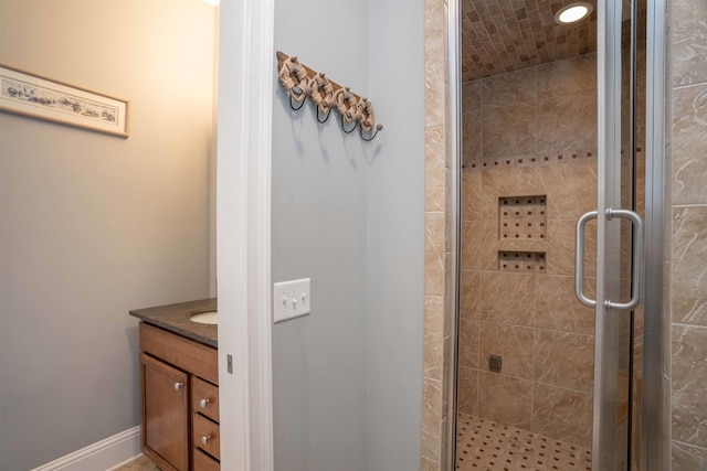 bathroom with a stall shower, vanity, and baseboards