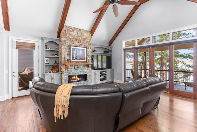 living room with a ceiling fan, wood finished floors, high vaulted ceiling, a fireplace, and beamed ceiling