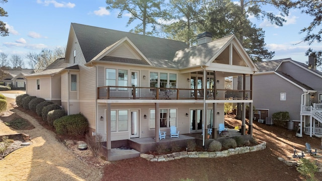 view of front facade featuring a shingled roof, a patio, cooling unit, and a chimney