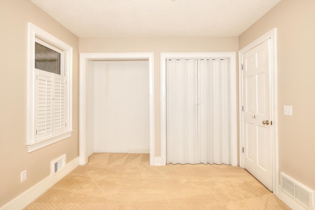 243 Riverbend Dr, Eatonton, GA 31024 - unfurnished bedroom with carpet floors, a textured ceiling, and multiple closets