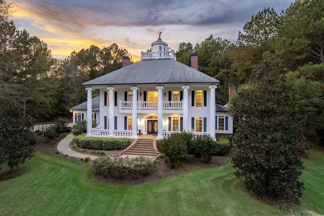 neoclassical home with a lawn, a balcony, and covered porch