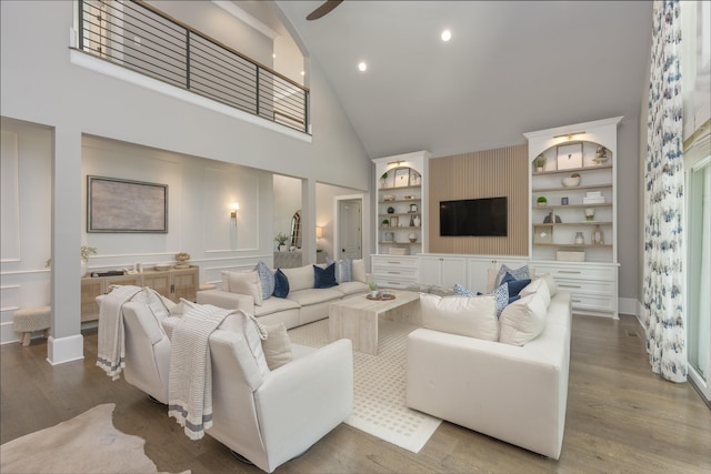 living room with ceiling fan, hardwood / wood-style floors, high vaulted ceiling, and built in shelves