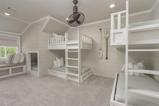 carpeted bedroom featuring lofted ceiling and wood walls